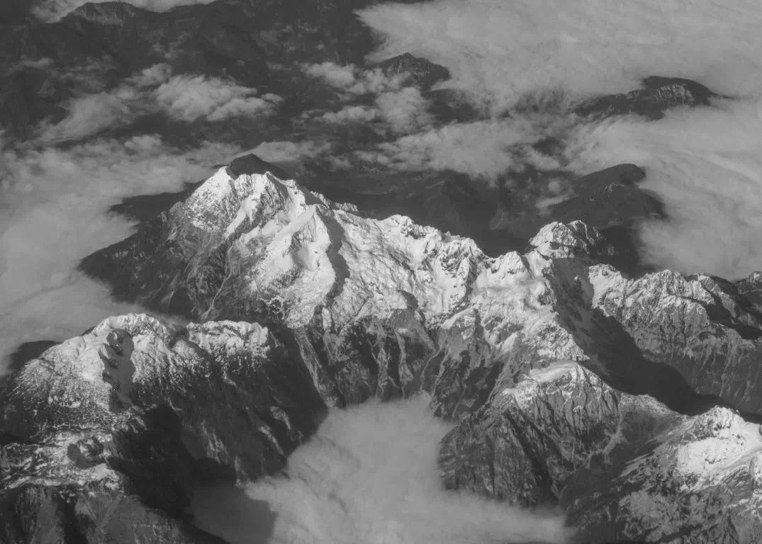 Aerial view of a snow-covered mountain range seen from above the clouds